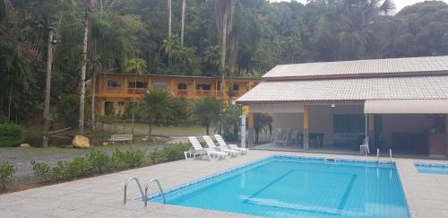 卡纳内亚Pousada Recanto do Morro的一座与度假村相连的建筑旁边的游泳池