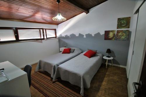 塞图巴尔Casa70的一间卧室配有两张带红色枕头的床