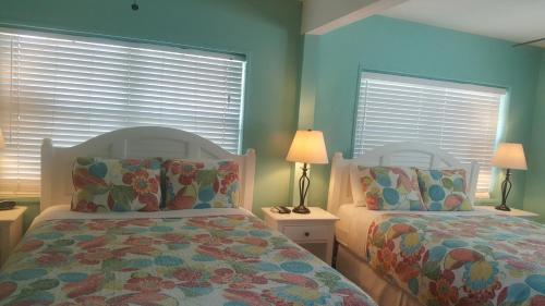 基韦斯特寇特妮之家历史小屋酒店的卧室设有两张床铺,拥有蓝色的墙壁和窗户