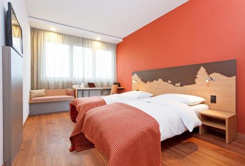 楚格瑞士祖格品质酒店的一间卧室设有两张床和橙色的墙壁