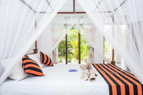 锡吉里亚锡吉里亚阳光别墅的一间卧室配有白色天蓬床,提供橙色和黑色枕头