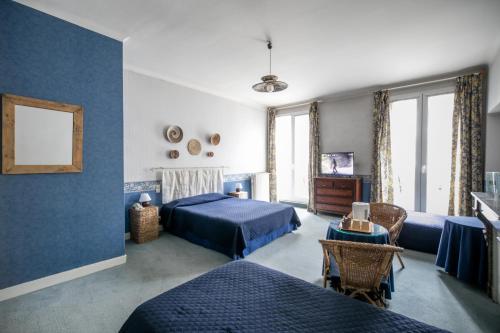 波城中央酒店的一间蓝色卧室,配有两张床和一张桌子