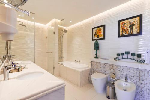 迪拜Royal Central Hotel and Resort The Palm的一间带水槽、浴缸和卫生间的浴室