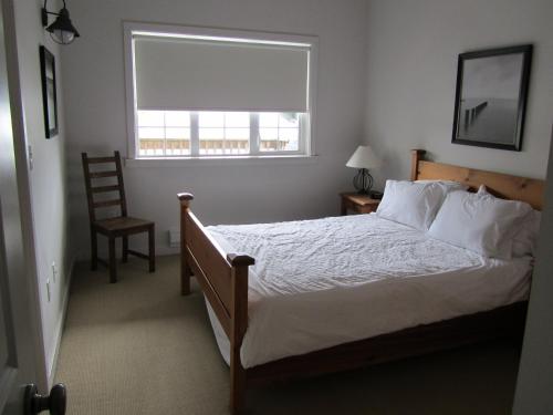 尤克卢利特水滨203公寓的一间卧室设有一张床、一个窗口和一把椅子