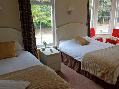 纽尼顿Abbey Grange Hotel的酒店客房带两张床和两个窗户