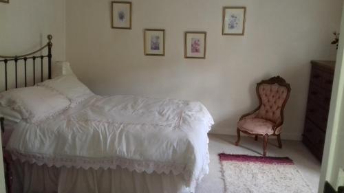拉恩Hills Farm B&B Laugharne的一间卧室配有一张床和一把椅子