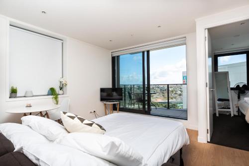 奥克兰Brand New Auckland Apartment的卧室设有一张白色大床和大窗户