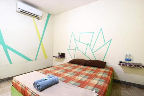 雅加达Wisma Gading Indah 1的卧室配有一张床,墙上挂有绘画作品