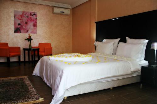 拉巴特乌贝酒店的卧室配有一张白色的大床,床上有黄色的鲜花