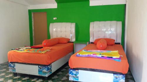 沙璜AAL Homestay的绿色和橙色客房的两张床