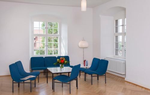 韦因加尔滕Akademie der Dioezese Weingarten的一间设有蓝色椅子和一张花瓶桌子的房间