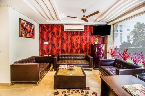 新德里FabExpress Le Continental的客厅配有皮革家具和红色墙壁