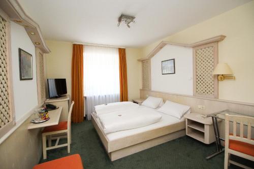 慕尼黑利奥波德酒店的一间卧室配有一张床、一张书桌和一台电视