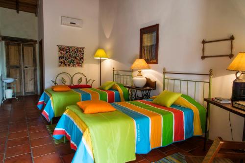 LadoeiroQuinta dos Trevos - Artes e Ofícios的一间卧室配有三张床和色彩缤纷的床单