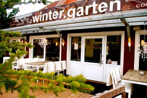斯拉德明Hotel Wintergarten的餐厅前面设有白色的桌椅