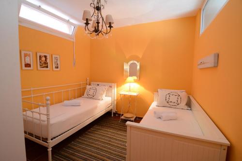 斯卡拉伯塔麦斯Villa Blue的配有橙色墙壁和吊灯的客房内的两张床