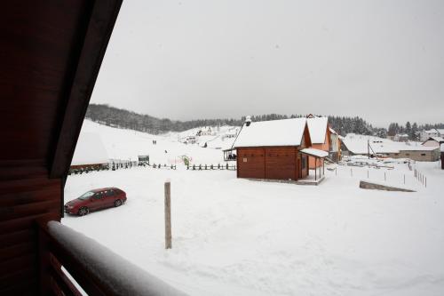 扎布利亚克家庭公寓酒店的停在一个有谷仓的雪地堆放场的汽车
