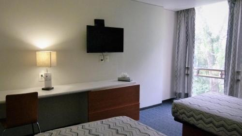 墨西哥城Aristos Express CDMX的酒店客房配有一张床和一张书桌及一台电视