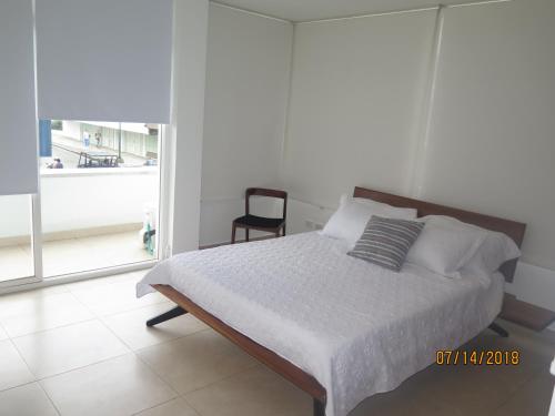 圣安德烈斯Tamarindo Centro Vip Apartment的一间卧室配有一张带椅子的床和一扇窗户