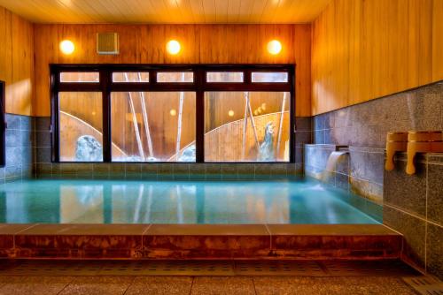 高山古都之梦温泉旅馆的一座带瀑布的建筑中的游泳池