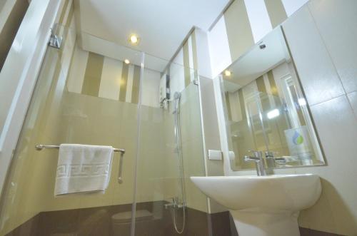 伊洛伊洛Injap Tower Hotel的一间带水槽和玻璃淋浴的浴室