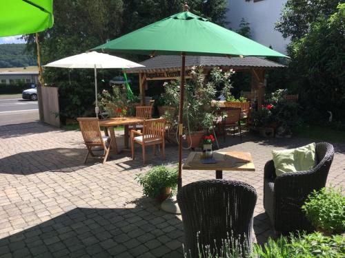 NiddaTektona "Bed & Breakfast"的一个带桌椅和绿色遮阳伞的庭院