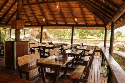 普利登堡湾Knysna Elephant Park Lodge的一间设有木桌、长凳和屋顶的餐厅