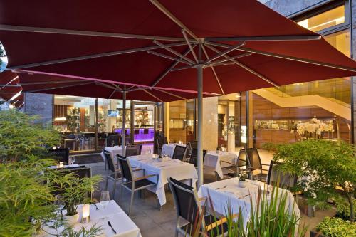 杜塞尔多夫杜塞尔多夫美利亚酒店的一间带桌椅和遮阳伞的餐厅