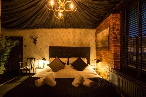 泰晤士河畔金斯顿福莱斯特阿姆斯旅馆的一间卧室配有一张带枕头和吊灯的大床