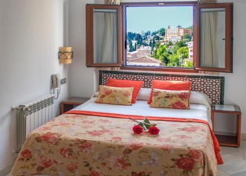 格拉纳达米拉多尔阿拉贝鲁赫酒店的一间卧室配有一张带红色枕头的床和一扇窗户