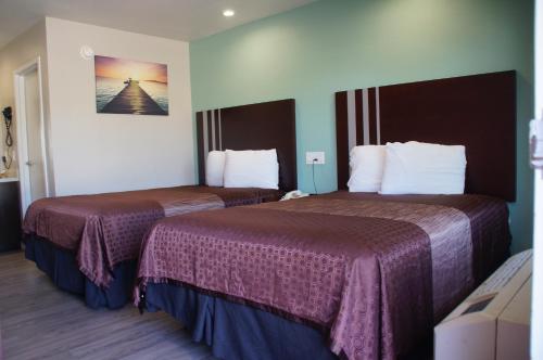长滩海滩旅馆汽车旅馆的酒店客房,配有两张带紫色床单的床