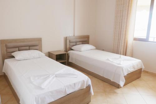 萨兰达Victoria's Sea-Cret的一间卧室设有两张带白色床单的床和窗户。