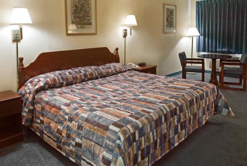 利兹America's Inn - Leeds的酒店客房带一张床、一张桌子和椅子