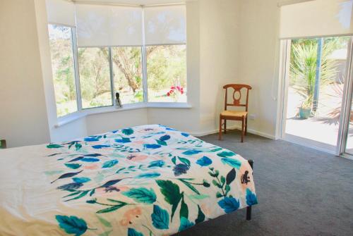 维克多港Back Valley Farmstay Bed and Breakfast的一间卧室配有一张带花卉棉被和窗户的床。