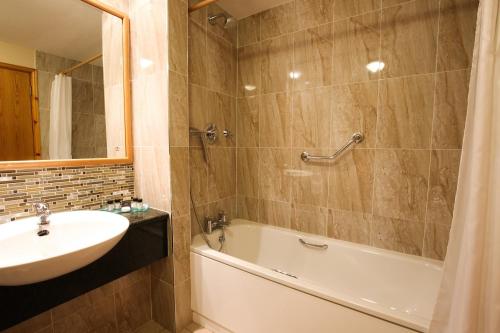 塔拉莫尔塔拉莫尔科尔酒店的浴室配有盥洗盆、浴缸和盥洗盆