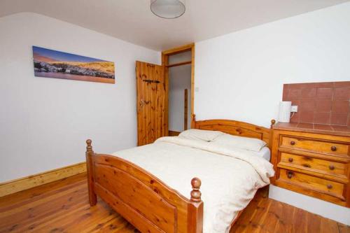 丁格尔Rainbow hostel的一间卧室配有木床和木制梳妆台
