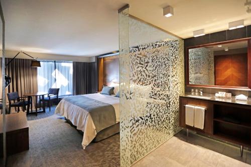 圣地亚哥坎布雷拉斯塔里亚酒店的酒店客房,设有床和玻璃墙