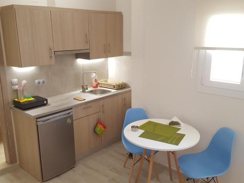 海若克利欧Minimalistic Studio Apartments的小厨房配有小桌子和蓝色椅子