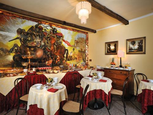 乌尔比诺波肯特酒店的餐厅设有桌子,墙上挂着一幅大画