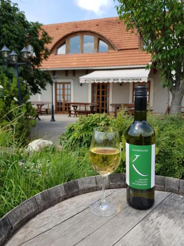 巴拉顿菲赖德Koczor Winery & Guesthouse的玻璃杯旁的一瓶白葡萄酒