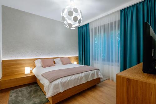 布加勒斯特Arbans Elegant apartment in the city center的一间卧室配有一张带蓝色窗帘的床和电视。