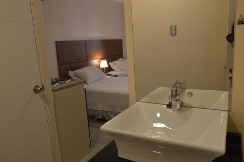 圣地亚哥Origen Apart-Hotel的一间带水槽的浴室和一间带一张床的卧室