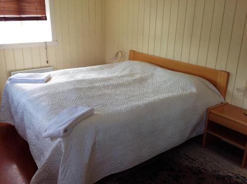 霍夫索斯Fraendgardur的卧室配有白色的床和木制床头板