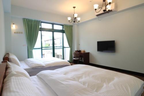 花莲市光与影的民宿(RGB)的一间卧室设有两张床、一台电视和一扇窗户。