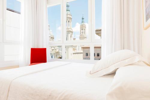 萨拉戈萨萨维纳斯埃尔皮拉尔公寓酒店的白色卧室设有红色椅子和大窗户