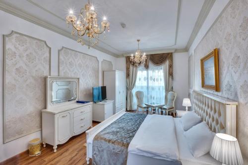 沙迦Royal Hotel的一间卧室配有一张床、一台电视和吊灯。