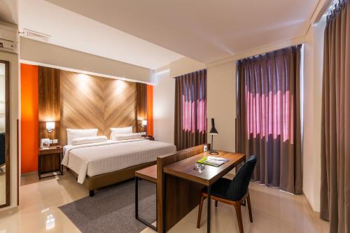 泗水Great Diponegoro Hotel Surabaya的酒店客房配有一张床、一张书桌和一张书桌。