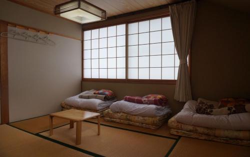 安昙野市Azumino Ikeda Guesthouse的客房设有两张床、一张桌子和一扇窗户。