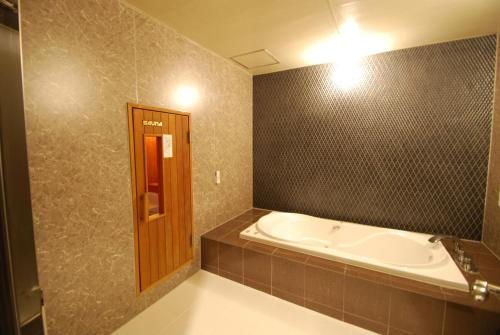 冈山自由式冈山酒店的带浴缸和瓷砖墙的浴室