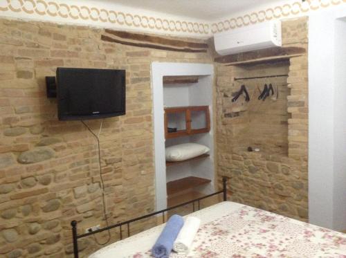 SpinetoliPantorano rooms的砖墙上设有电视的卧室
